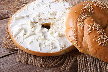 a sesame bagel sliced in half and spread with cream cheese