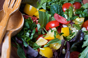 a mixed green salad in a wooden bowl