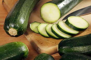 a pile of various sizes of fresh zucchini, some with flowers still attached to them