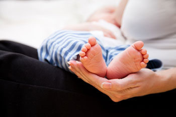 An infant lying on a person's lap, breastfeeding