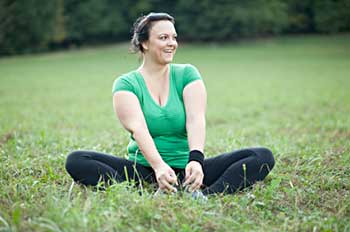 A woman sitting in the grass, stretching